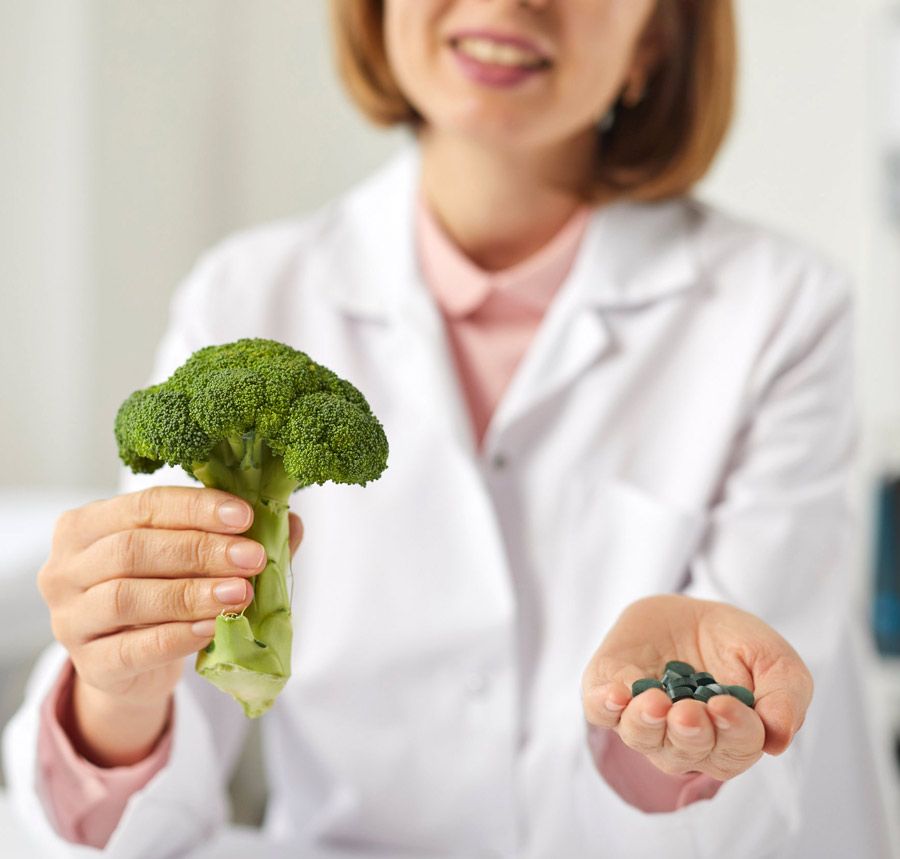 Mujer con medicamentos y verduras en la mano
